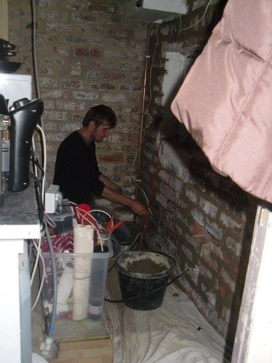 An electrician running cables against exposed brickwork during a renovation
