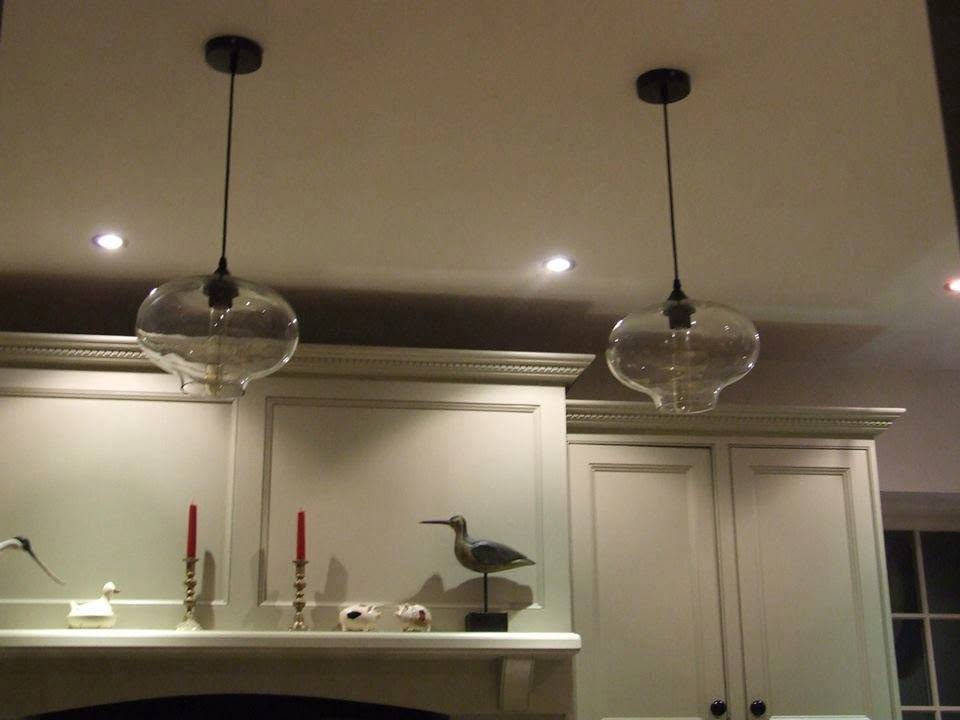 Two glass pendant lights and downlights over a kitchen dresser shelf