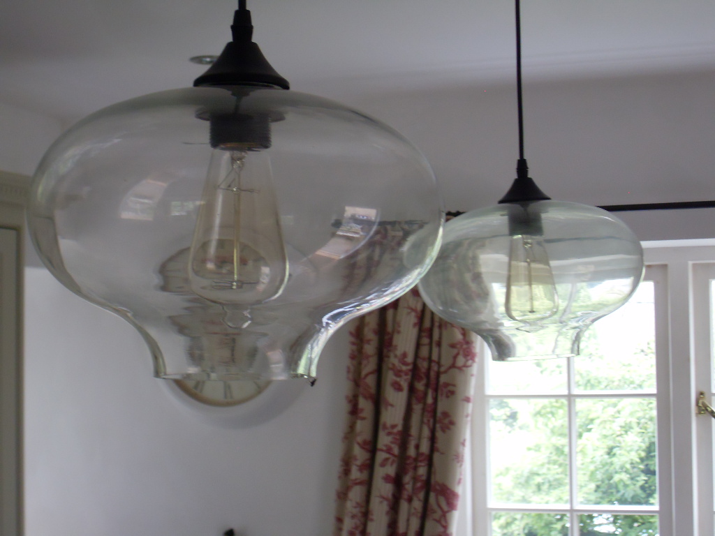 Two blown-glass pendant lights hanging in a room with sash windows