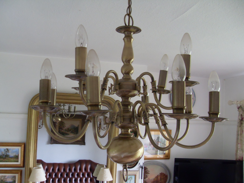 A large brass multi-arm chandelier lit in a sitting room
